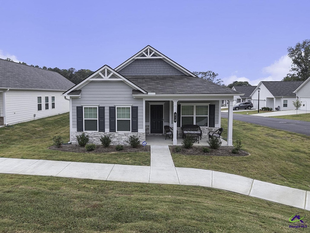 view of front facade featuring stone siding, covered porch, and a front yard