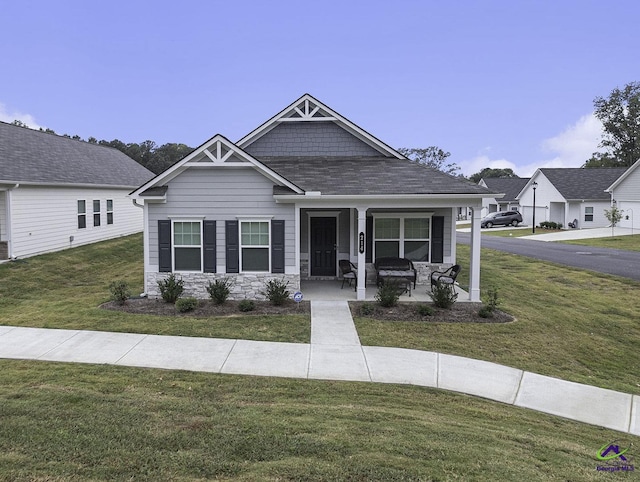 view of front facade featuring stone siding, covered porch, and a front yard