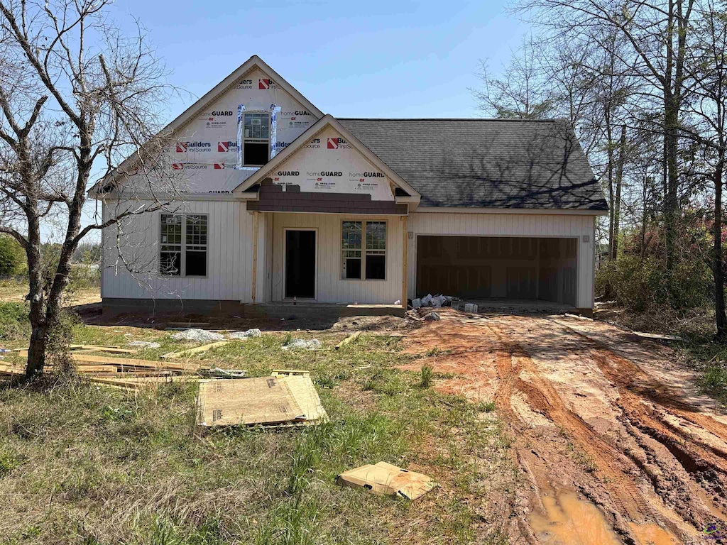 view of front of property with a garage, roof with shingles, and driveway