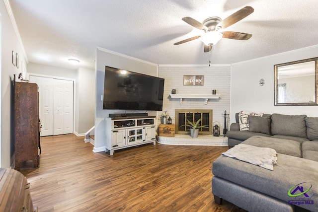 living room featuring a textured ceiling, ceiling fan, wood finished floors, ornamental molding, and baseboards