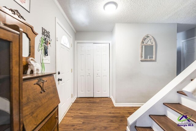 entryway featuring dark wood finished floors, stairs, a textured ceiling, and baseboards
