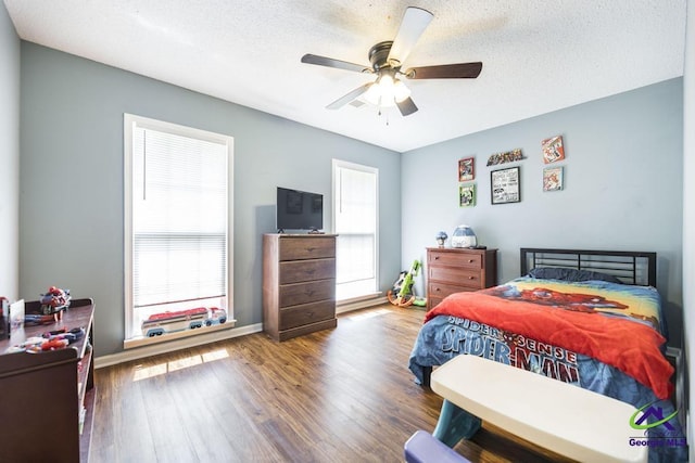 bedroom with wood finished floors, a textured ceiling, a ceiling fan, and baseboards