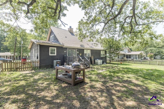 rear view of property with a deck, central air condition unit, a chimney, and roof with shingles