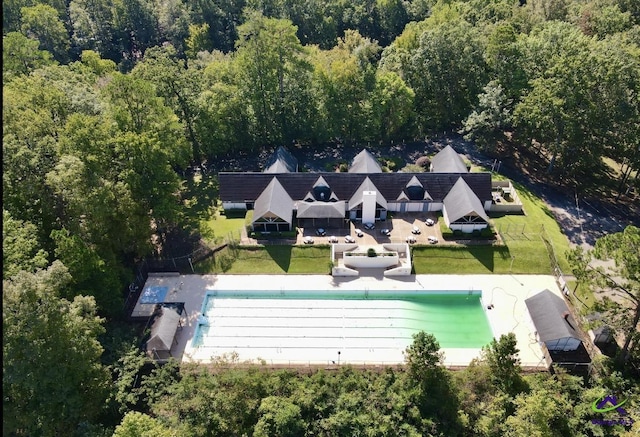 view of subject property featuring a heavily wooded area and a pool