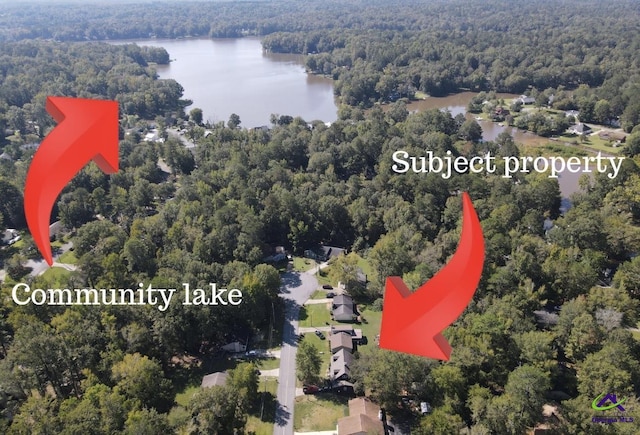 aerial view of property and surrounding area with a forest and a nearby body of water