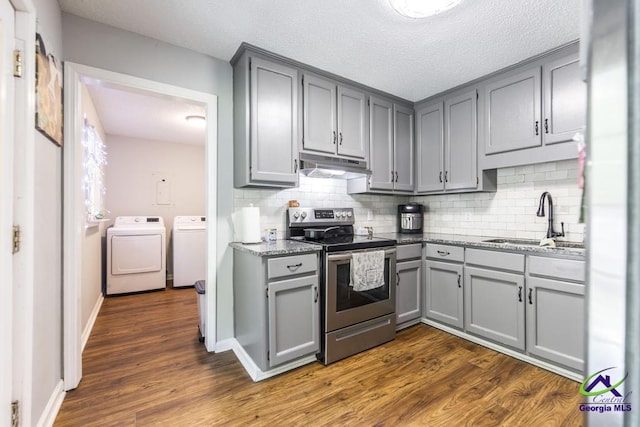 kitchen with stainless steel range with electric stovetop, gray cabinetry, independent washer and dryer, under cabinet range hood, and a sink