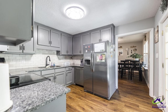 kitchen featuring stainless steel appliances, a sink, gray cabinets, and decorative backsplash