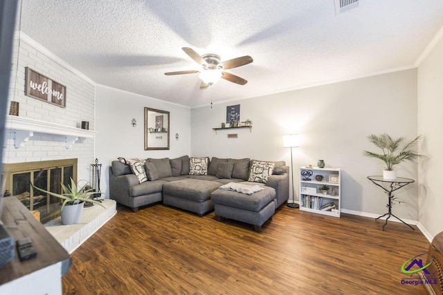 living area with a ceiling fan, ornamental molding, wood finished floors, a textured ceiling, and a fireplace