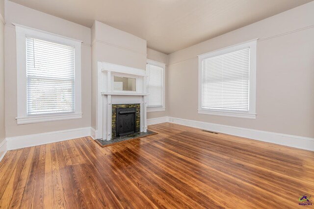 unfurnished living room featuring visible vents, baseboards, wood finished floors, and a fireplace