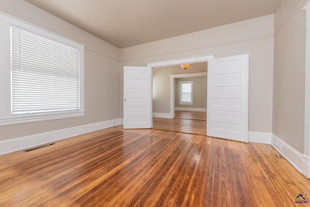 empty room featuring visible vents, baseboards, and wood finished floors