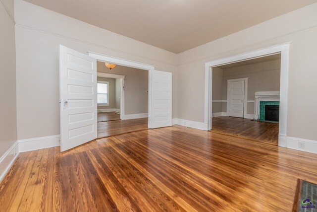 empty room featuring a fireplace with flush hearth, baseboards, and wood finished floors