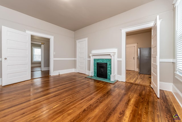 unfurnished living room with a fireplace, wood finished floors, and baseboards