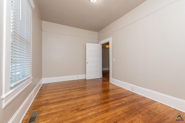unfurnished room with wood finished floors, visible vents, and baseboards