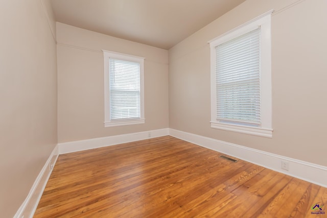 spare room with visible vents, baseboards, and wood finished floors