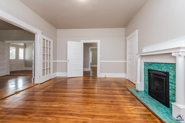 unfurnished living room featuring wood finished floors, baseboards, and a fireplace with raised hearth