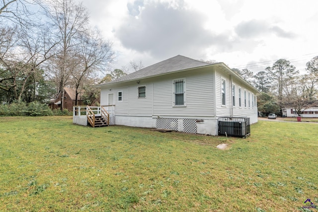 rear view of house with a yard, central AC unit, a deck, and a shingled roof