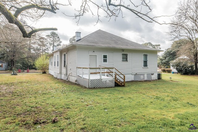 back of property featuring a wooden deck, a lawn, a chimney, and a shingled roof