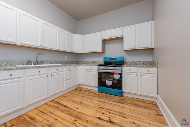 kitchen featuring white cabinetry, light wood-style flooring, stainless steel electric range, and a sink