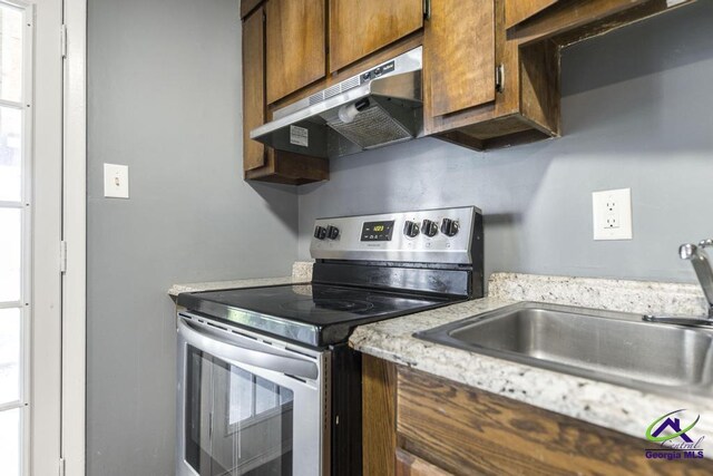 127 Stoneridge Dr, Warner Robins, GA 31088 - kitchen with under cabinet range hood, stainless steel electric range oven, brown cabinets, and a sink