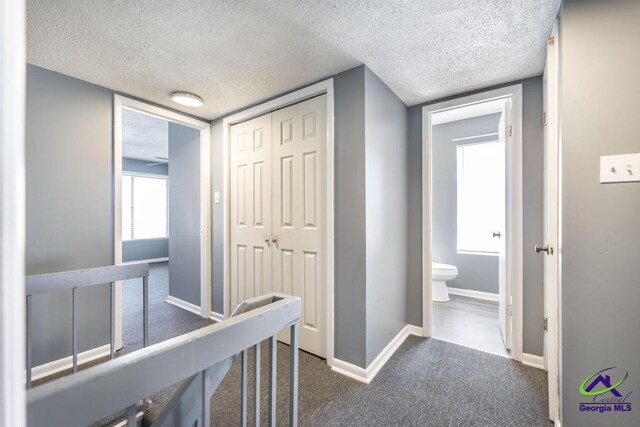 127 Stoneridge Dr, Warner Robins, GA 31088 - corridor featuring a textured ceiling, baseboards, and dark colored carpet