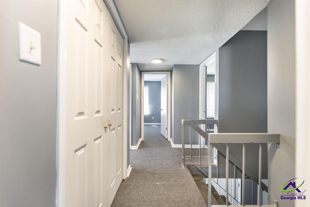 127 Stoneridge Dr, Warner Robins, GA 31088 - hall with an upstairs landing, baseboards, dark carpet, and a textured ceiling