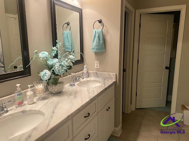full bathroom featuring a sink, double vanity, and tile patterned flooring