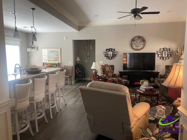 living room with beamed ceiling, crown molding, light wood-style floors, and ceiling fan