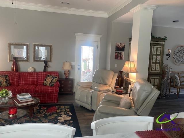 living area with decorative columns, wood finished floors, visible vents, and ornamental molding