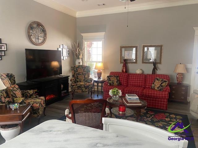 living room with crown molding, wood finished floors, and visible vents