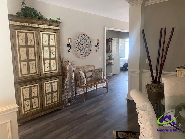 sitting room featuring dark wood-type flooring, a decorative wall, and a wainscoted wall