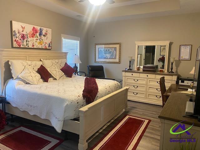 bedroom featuring a tray ceiling, dark wood-type flooring, and ceiling fan