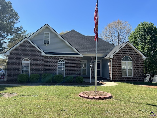 view of front of house with brick siding, roof with shingles, and a front yard