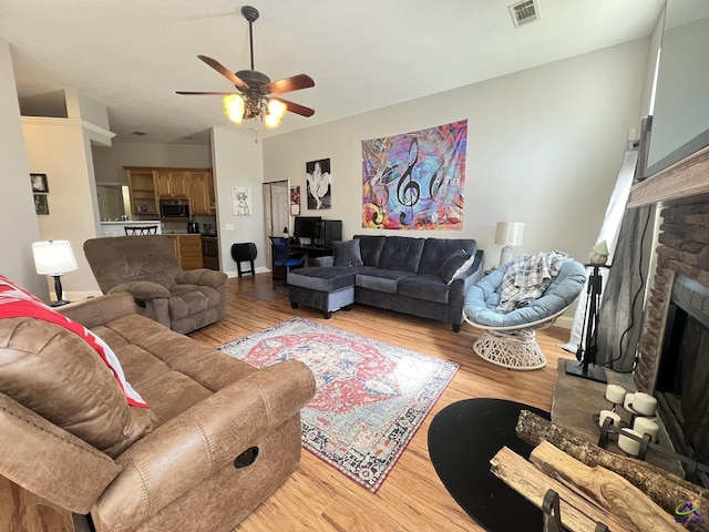 living room with visible vents, light wood-style flooring, and ceiling fan
