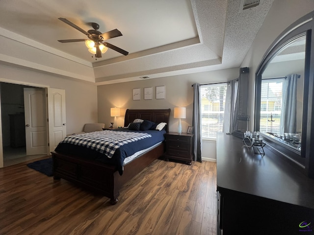 bedroom featuring visible vents, a raised ceiling, and wood finished floors