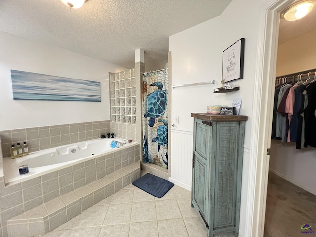 bathroom featuring curtained shower, a textured ceiling, a jetted tub, tile patterned flooring, and a spacious closet