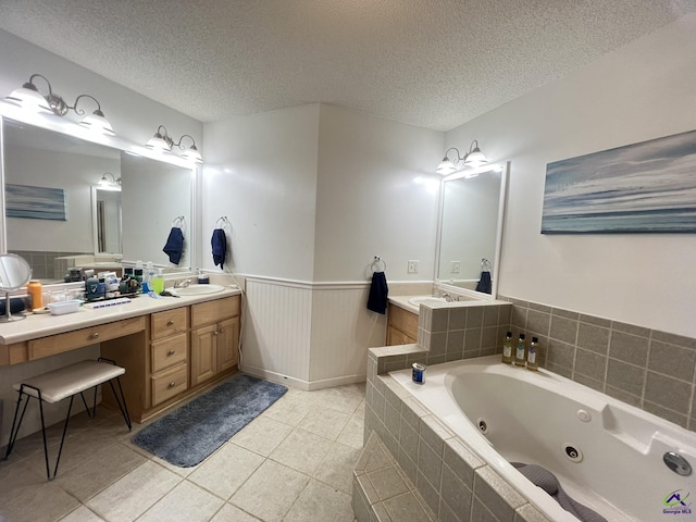 full bath with tile patterned floors, a wainscoted wall, a textured ceiling, and a tub with jets
