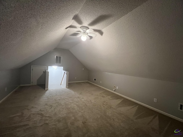 additional living space with visible vents, a textured ceiling, carpet, ceiling fan, and vaulted ceiling