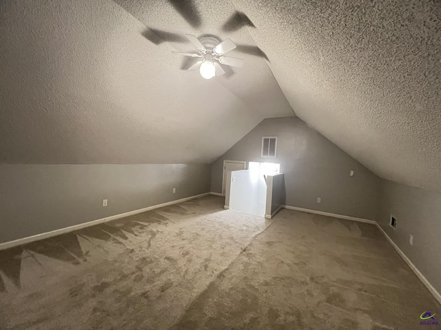 bonus room with visible vents, a textured ceiling, carpet flooring, ceiling fan, and vaulted ceiling