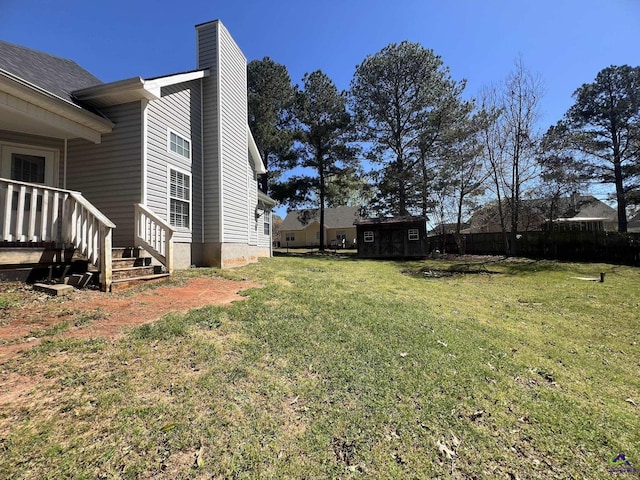view of yard featuring an outbuilding, a storage unit, and fence