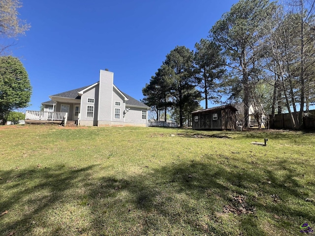 view of yard with a deck, an outbuilding, a storage shed, and fence