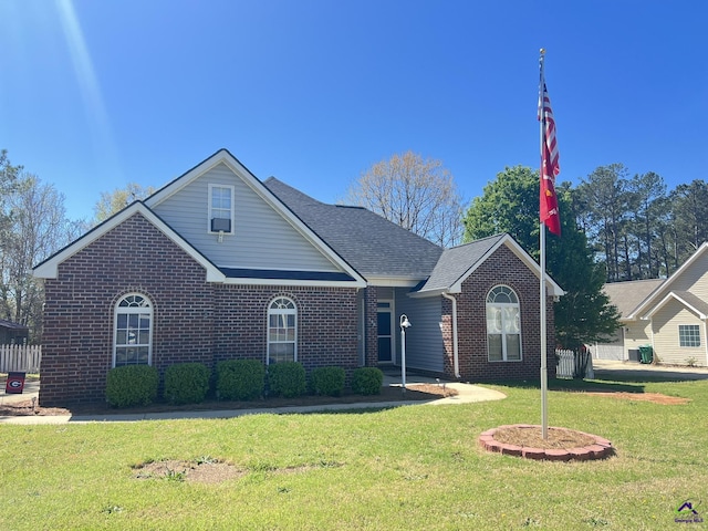 view of front of home with brick siding, roof with shingles, and a front yard