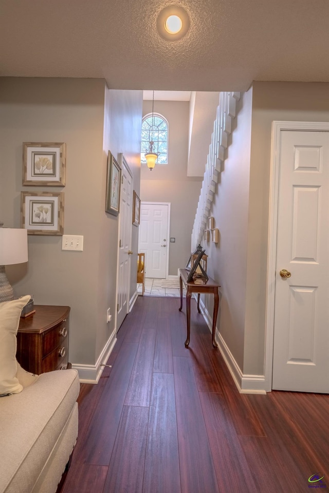 foyer entrance featuring stairway, baseboards, a textured ceiling, and dark wood-style floors