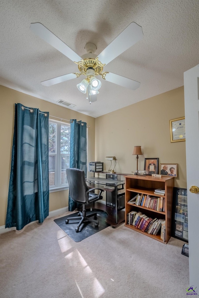 office space with a ceiling fan, baseboards, visible vents, carpet floors, and a textured ceiling