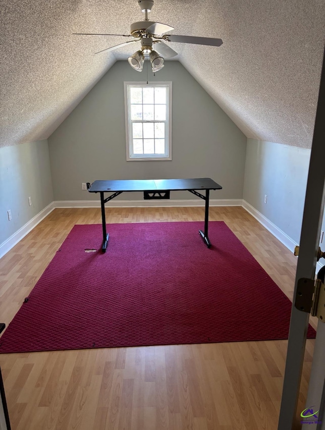 workout area featuring ceiling fan, lofted ceiling, a textured ceiling, and wood finished floors