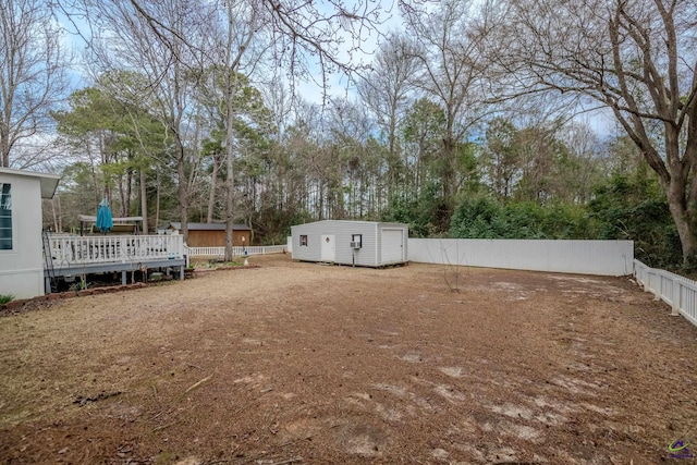 view of yard with a wooden deck, an outdoor structure, a fenced backyard, and a storage shed