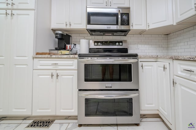 kitchen featuring marble finish floor, tasteful backsplash, appliances with stainless steel finishes, white cabinets, and light stone countertops