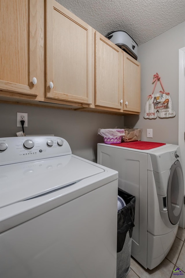 laundry area featuring light tile patterned flooring, cabinet space, a textured ceiling, and independent washer and dryer