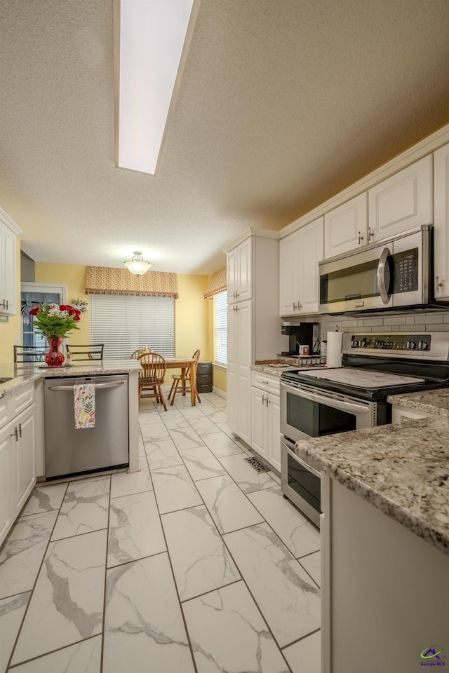 kitchen with white cabinets, marble finish floor, and appliances with stainless steel finishes