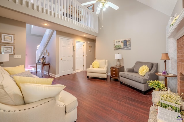living room with baseboards, dark wood-type flooring, a ceiling fan, and a towering ceiling