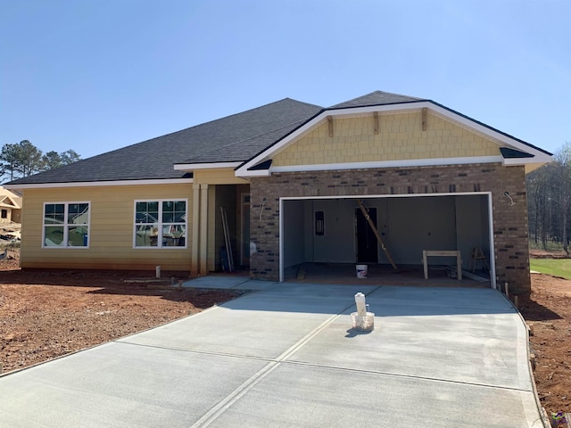 view of front facade with brick siding, a garage, driveway, and a shingled roof
